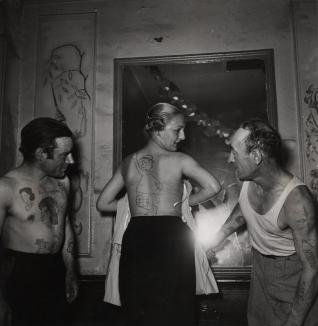 Robert Doisneau Concours de tatouages dans un bar de la rue Mouffetard. « Au milieu de vrais tatoués, une jeune femme s’est amusée à présenter un faux tatouage » 1950 © Atelier Robert Doisneau